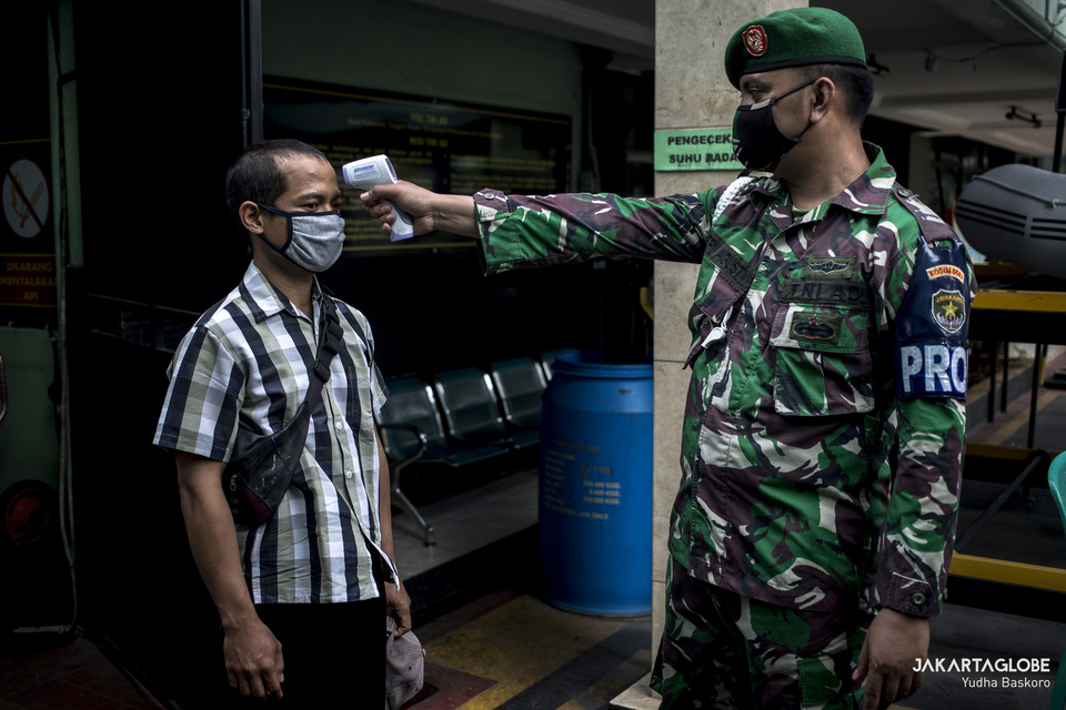 An Indonesian solider checks body temperature of a resident in West Jakarta on Monday. (JG Photo/Yudha Baskoro)