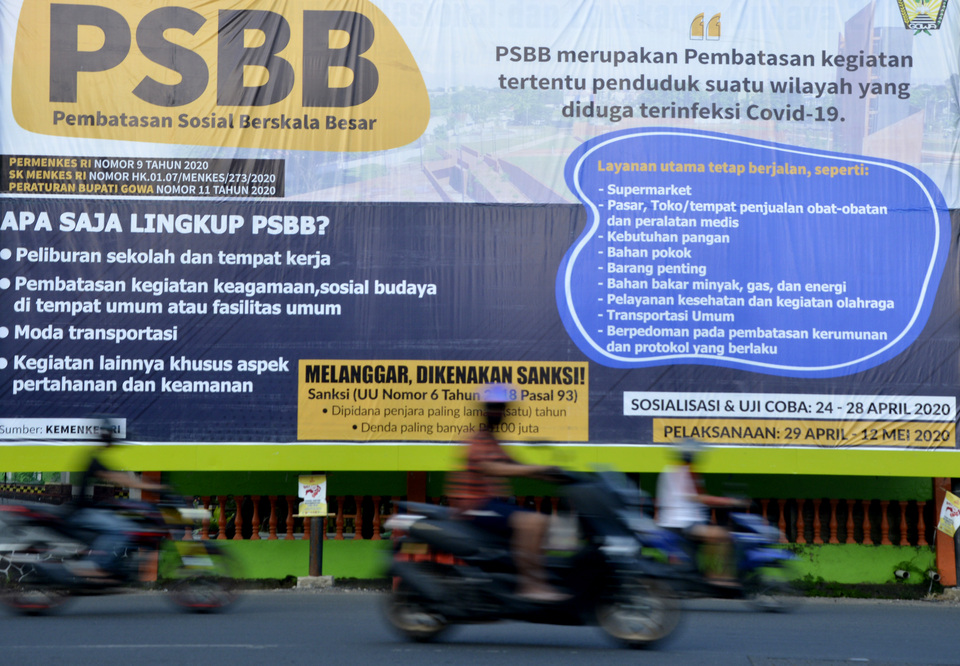 Motorcyclists ride past a large-scale social restriction (PSBB) poster in Gowa, South Sulawesi, last week. (Antara Photo/Abriawan Abhe)