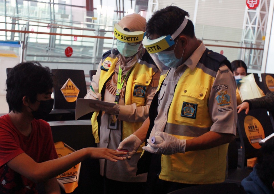 Medical officers at Soekarno-Hatta International Airport conduct a rapid tests for Covid-19 on a passenger on Thursday. (Antara Photo/Muhammad Iqbal)
