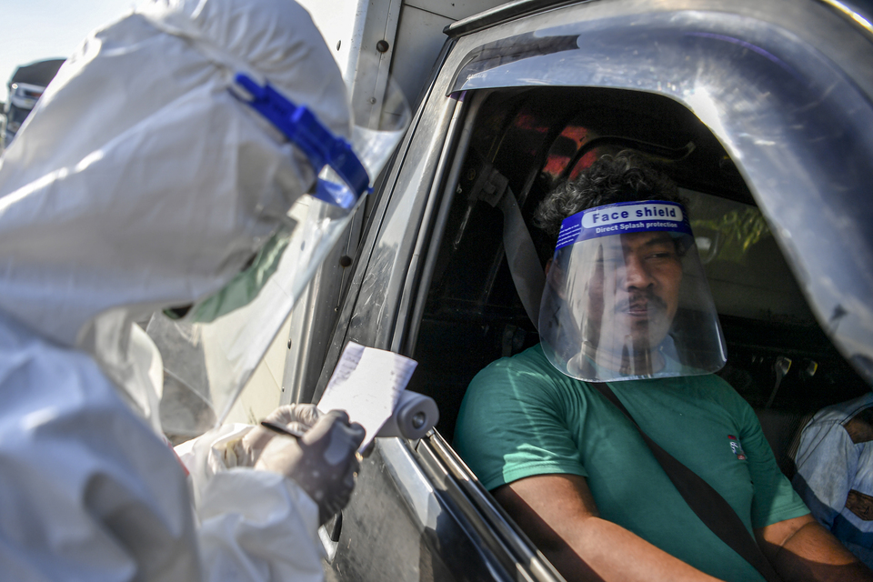 An official in hazmat suit checks a traveler's travel documents on Jalan Raya Pantura in Cirebon, West Java, on Tuesday. (Antara Photo/Nova Wahyudi)