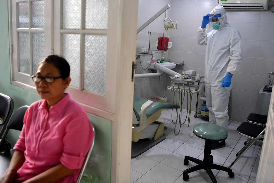 A dentist in Surabaya, East Java, wears complete personal protective equipment before examining a patient on Friday. (Antara Photo/Zabur Karuru)