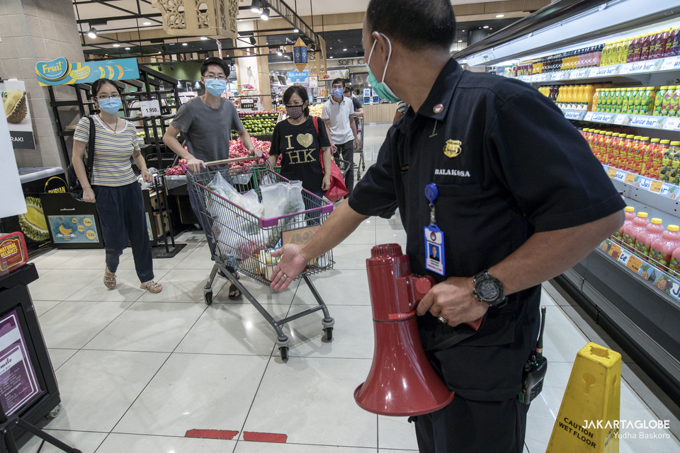 An AEON mall security officer uses a bullhorn to warn visitors who don't comply with the health protocol on May 26. (JG Photo/Yudha Baskoro)