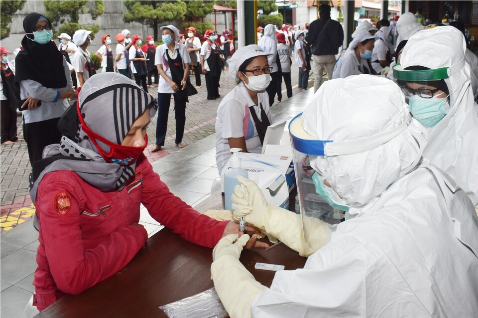 A health worker takes blood sample from a worker for rapid screening of coronavirus at a cigarette factory in Madiun, East Java, on Wednesday. (Antara Photo/Siswowidodo)