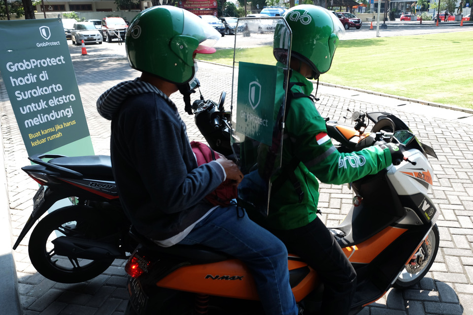 A GrabBike scooter taxi equipped with a plastic screen between driver and pillion in Solo, Central Java, on Monday. (Antara Photo/Maulana Surya)