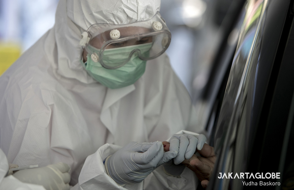 A health worker takes a blood sample through a car window in Bogor, West Java, on April 8. (JG Photo/Yudha Baskoro)