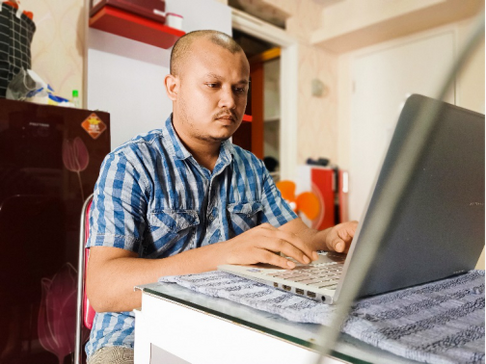 J.N. Joniad, a Rohingya writer and editor of The Archipelago writes an article on his laptop. (Photo by J.N. Joniad)