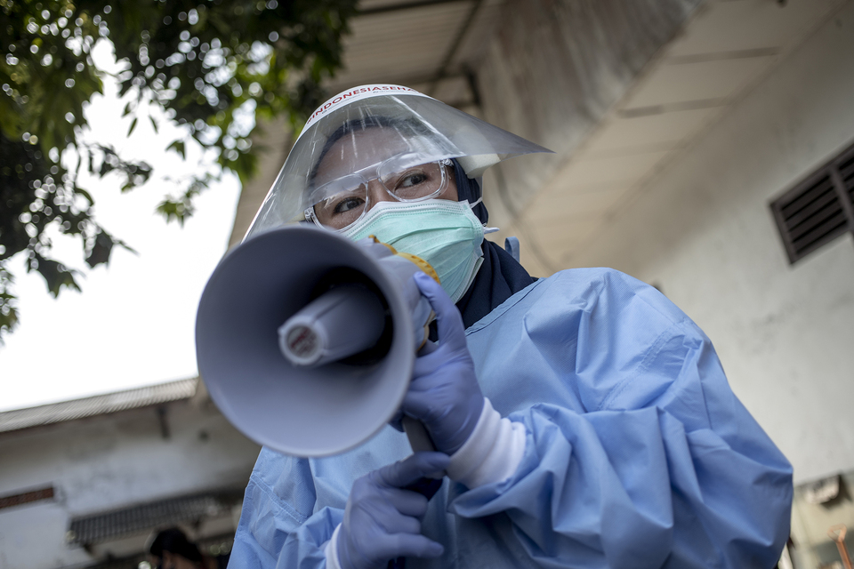 A health worker speaks through megaphone as he gathers people to have rapid screening for Covid-19 in a Jakarta traditional market. (JG Photo/Yudha Baskoro)