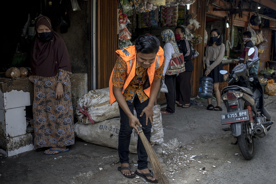 A man is taking social punishment by sweeping the street in Jakarta after he is caught not wearing a mask in the public. (JG Photo/Yudha Baskoro)