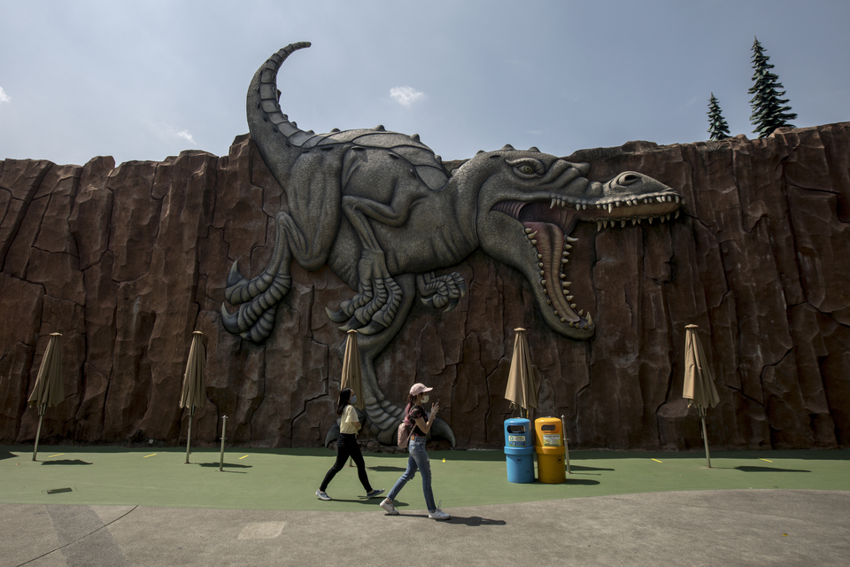 FILE - Visitors walk in front of a wall dinosaur sculpture at the Ancol Amusement Park  in North Jakarta. (JG Photo)