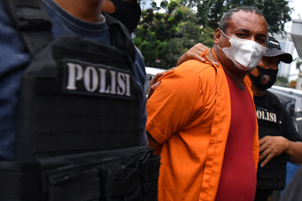 Murder suspect John Kei is escorted by two officers at the Jakarta Police compound on June 22, 2020. (Antara Photo/Sigid Kurniawan)