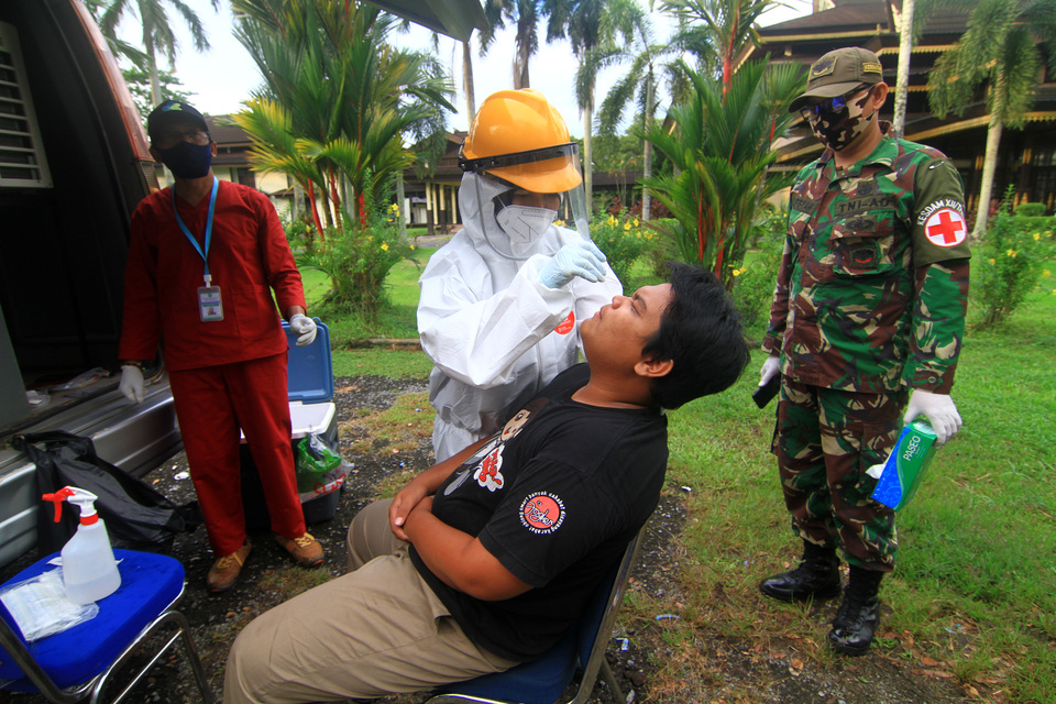 A medical worker collects mucosal swab from a man in Pontianak, West Kalimanatan on Monday. (Antara Photo/Jessica Helena Wuysang)