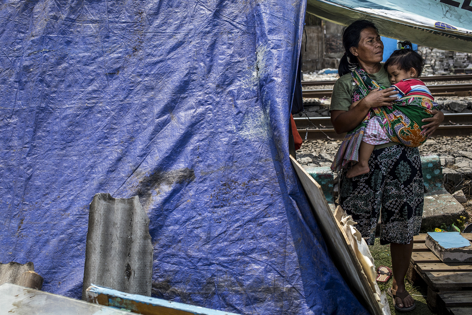 A woman carries her child outside a  tent in Kampung Bandan, North Jakarta on Monday. (JG Photo/Yudha Baskoro)