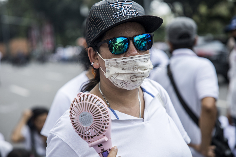 A woman carries a portable fan as she participates in a rally by entertainment industry workers demanding business reopening in front of City Hall on July 21, 2020. (JG Photo/Yudha Baskoro)