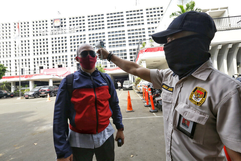 A worker at Indonesia's General Election Commission head office in Jakarta measures a visitor's body temperature last Friday. (SP Photo/Ruht Semiono)