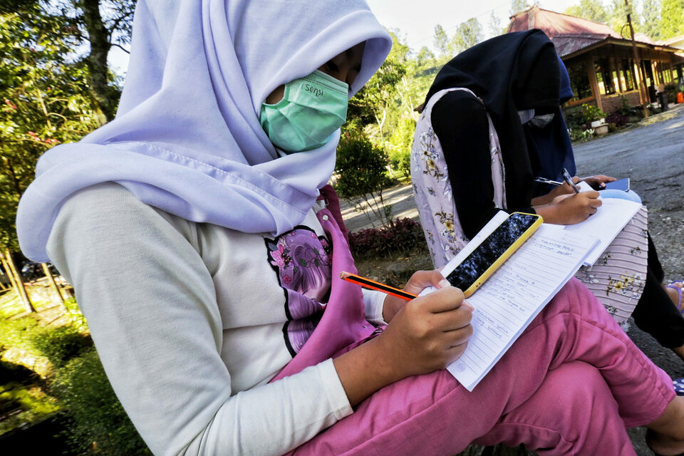 Junior high school students do their online homework at the roadside in search for better internet signal in Gunung Mas area, Bogor, West Java, on July 28, 2020. Most schools in Indonesia apply remote learning during the Covid-19 pandemic. (Beritasatu Photo/Ruht Semiono)