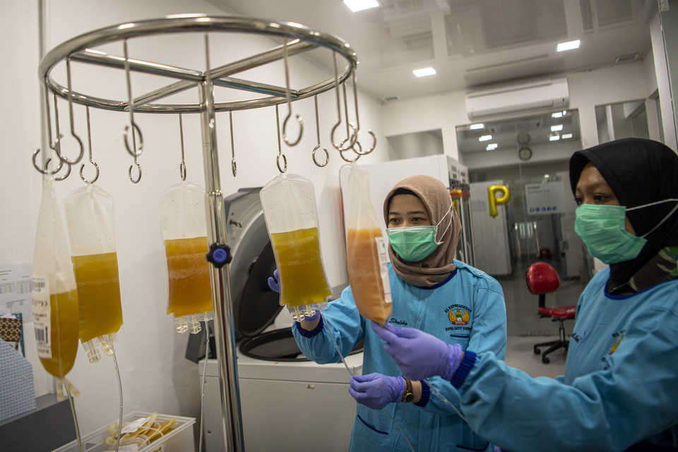 Two medical workers inspect convalescent plasma donated by Covid-19 survivors at Gatot Soebroto Army Hospital in Jakarta on August 18, 2020. The hospital applies convalescent plasma transfusion as the treatment of Covid-19 patients. (Antara Photo/Nova Wahyudi)