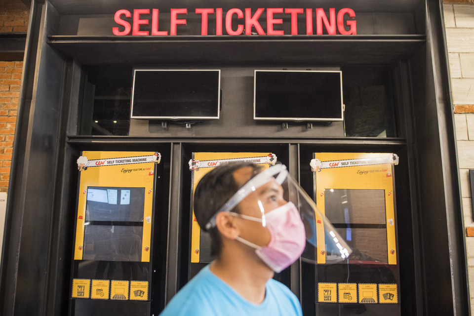 An employee wears mask and face shield when inspecting ticket machine at a CGV Cinemas' movie theater in Bandung, West Java, in July. (Antara Photo/M. Agung Rajasa)