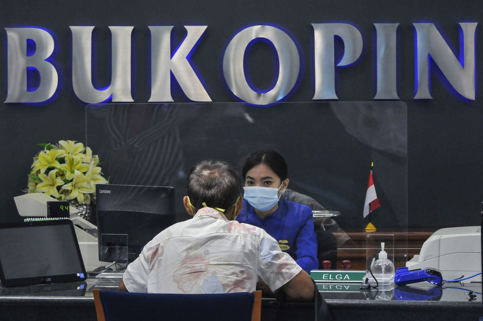A bank officer serves a man at Bank Bukopin's headquarter in South Jakarta on July 1, 2020. (Antara Photo/Fakhri Hermansyah)