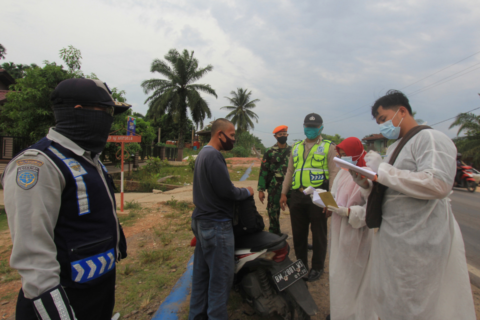 City officials in Dumai, Riau, stop a motorcyclist for document checks on Sept. 8, 2020. The city increased surveillance at the border to restrict people movement amid surging Covid-19 cases. (Antara Photo/Aswaddy Hamid)