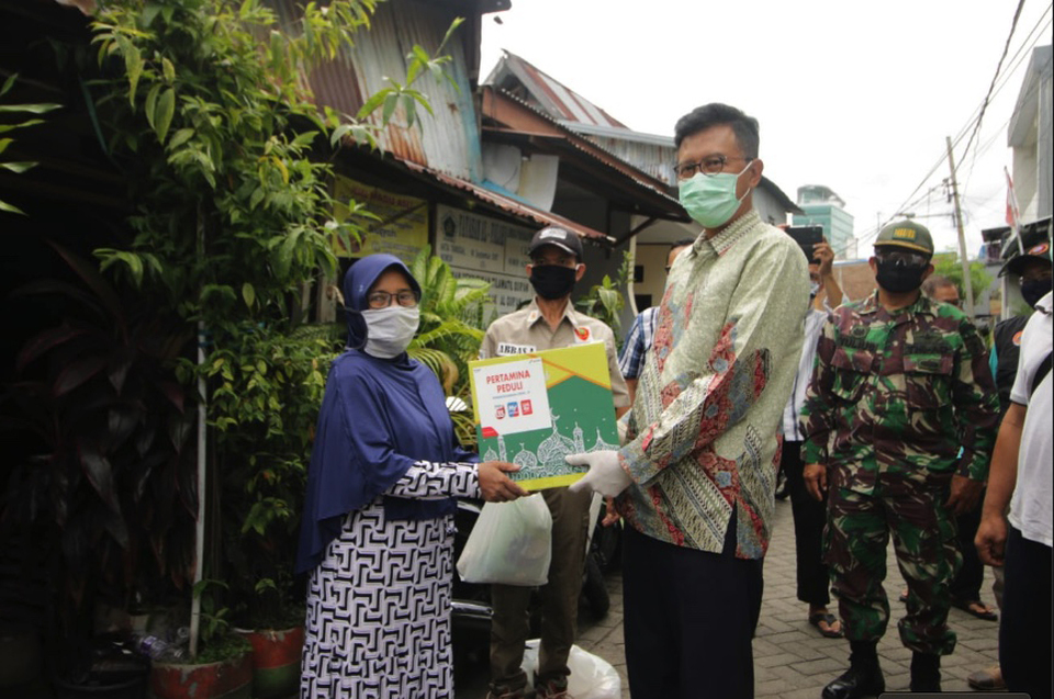 C.D. Sasongko, a general manager at Pertamina, right, gives away a food package to a resident in Makassar, Southeast Sulawesi as part of the Indonesian energy company's CSR program last April. (B1 Photo)