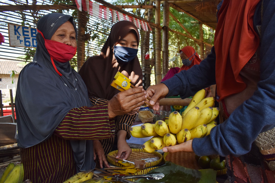 A banana seller receives payment in bamboo tokens from a woman in Pundensari traditional market in Madiun, East Java last month. (Antara Photo/ Siswowidodo)