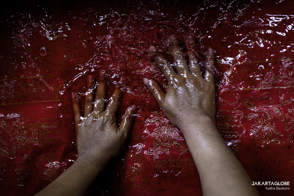 A man puts a batik fabric inside a colored water in Batik Betawi Terogong workshop in Cilandak, South Jakarta on Friday (02/10). (JG Photo/Yudha Baskoro)