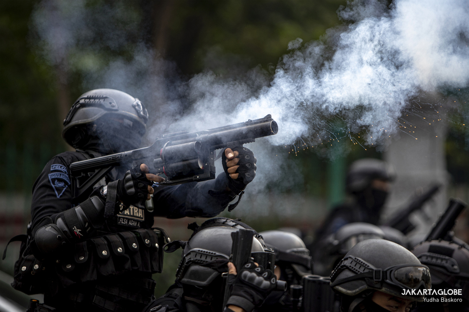 A riot policeman fires tear gas during a violent rally against the job creation law in Central Jakarta on  Oct. 13, 2020. (JG Photo/Yudha Baskoro)