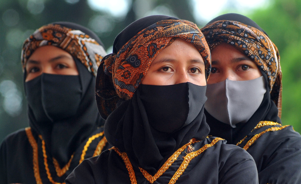 Three women wearing face masks get prepared before performing traditional martial art Pencak Silat in Padang, capital of West Sumatra, on Sept. 12, 2020. (Antara Photo/Iggoy el Fitra)