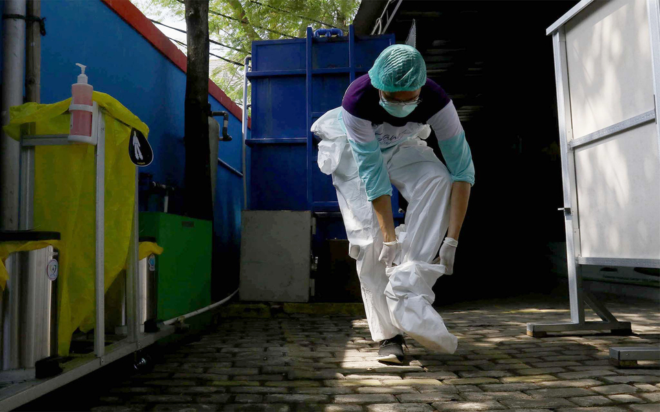 A medical staff carefully takes off his protective suit after treating Covid-19 patients at a public health center (Puskesmas) in Gambir, West Jakarta, on Oct. 15, 2020. (Beritasatu Photo/Joanito De Saojoao)
