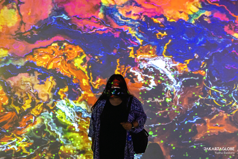 A woman stands in front of a large video display during an exhibition of Affandi’s paintings at the National Galery building in Central Jakarta on Nov. 6, 2020. (JG Photo/Yudha Baskoro)
