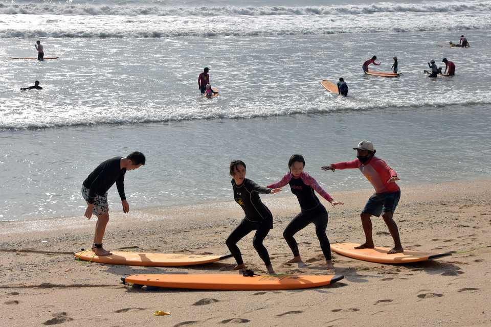 FILE - Tourists practice surfing on Kuta Beach, Bali, on Oct. 30, 2020. (Antara Photo)