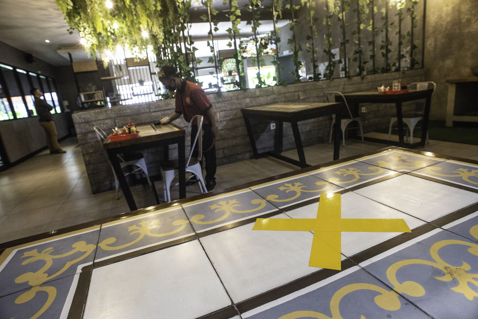 A waitress cleans a table in an empty resturant in West Jakarta last month. (Antara Photo/Aprillio Akbar)