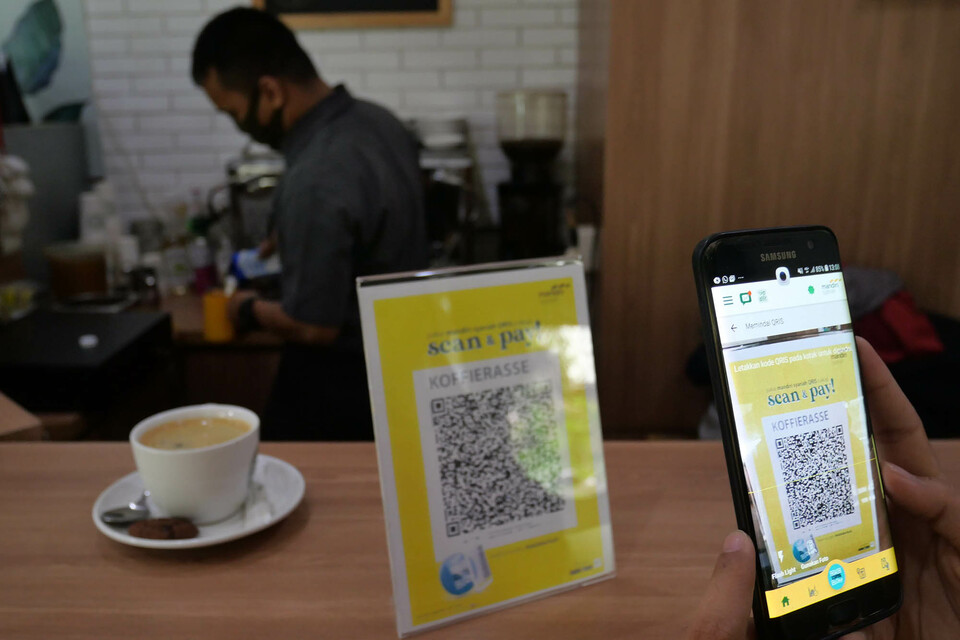 A shopper scans a quick response code Indonesian standard (QRIS) to pay for a cup of coffee in a cafe in Jakarta last July. (ID Photo/David Gita Roza)