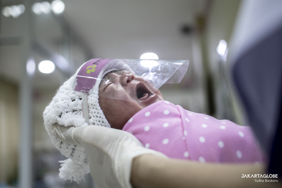 A nurse holds a newborn baby wearing a mini face shield at Tambak Children's Hospital in Menteng, Central Jakarta, on April 15, 2020. (JG Photo/Yudha Baskoro)