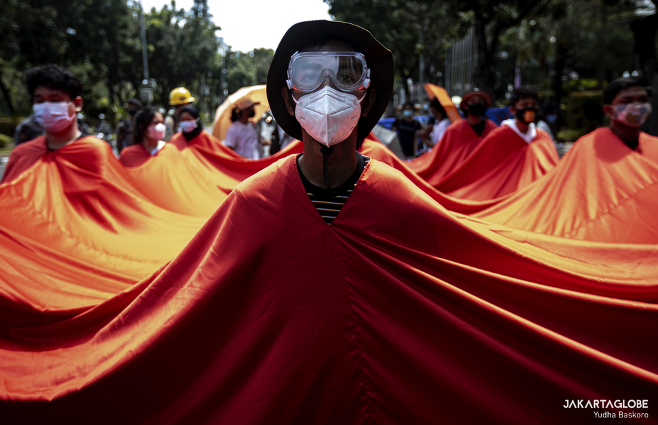 Protesters wear a big red flag during a theatrical performance in front of Jakarta City Hall on Friday. Environmental activists, students, and children joined the "Asia Climate Rally" in front of the Jakarta City Hall on November 29, 2020 to raise awareness about climate change and voice demands to the government to step up its efforts in mitigating the crisis. (JG Photo/Yudha Baskoro)
