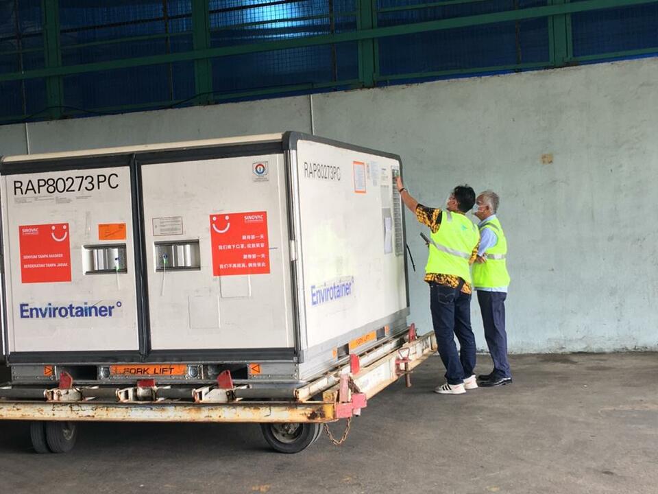 Two National Covid-19  Task Force officials inpect a box containing half-finished Sinovac vaccine upon arrival at the Soekarno-Hatta Airport from China on Jan. 12, 2021. (Photo courtesy of the National Disaster Mitigation Agency)