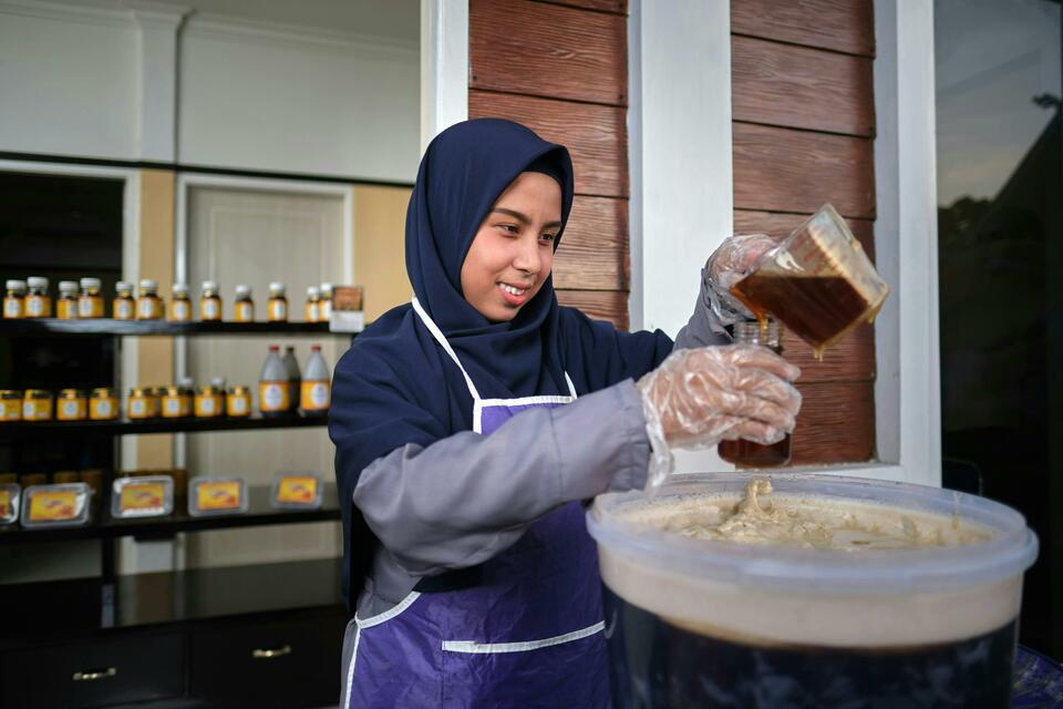 A woman puts honey into a glass jar at RAPP's Rumah Madu Andalan. (Photo Courtesy of RAPP)