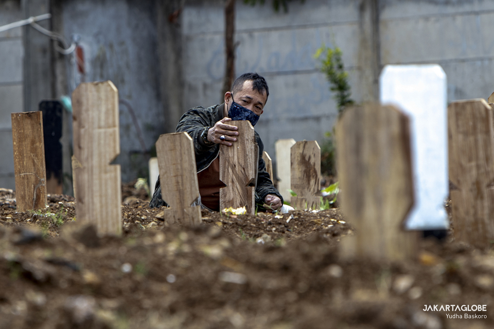 A man mourns at Srengseng Sawah Public Cemetery in South Jakarta on Jan. 26, 2021. (JG Photo/Yudha Baskoro)