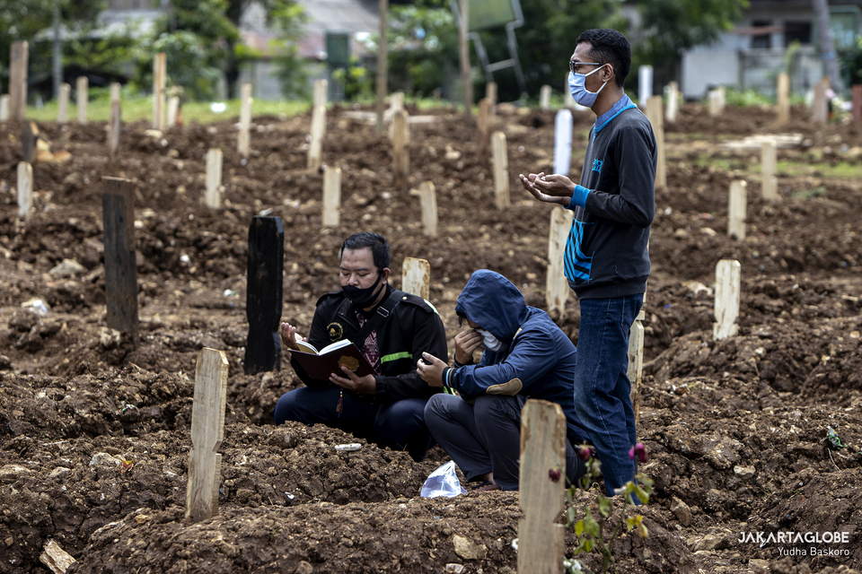 Relatives mourn near the new grave of a Covid-19 victim at Srengseng Sawah public cemetery in South Jakarta on Jan. 26, 2021. (JG Photo/Yudha Baskoro)