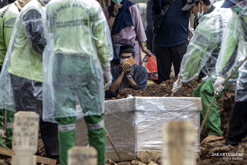 Mourners pray next to the coffin of Covid-19 victim at Srengseng Sawah public cemetery in South Jakarta on Jan. 26, 2021. (JG Photo/Yudha Baskoro)