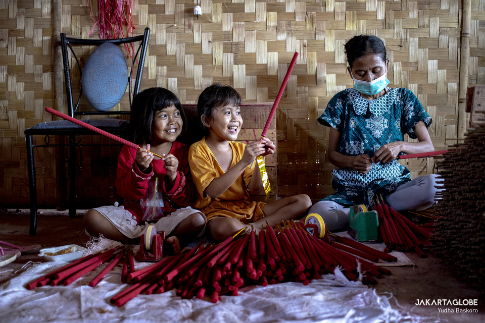 A female worker wraps incense sticks as two children play next to her at a home factory in Tangerang on Feb, 1, 2021. (JG Photo/Yudha Baskoro)