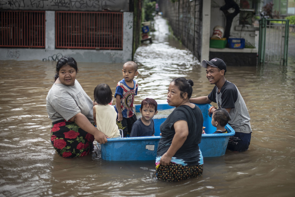 Jakarta residents use a large plastic bucket as a makeshift raft to entertain the children during floods in South Jakarta on Saturday. (Antara Photo/Aprillio Akbar)