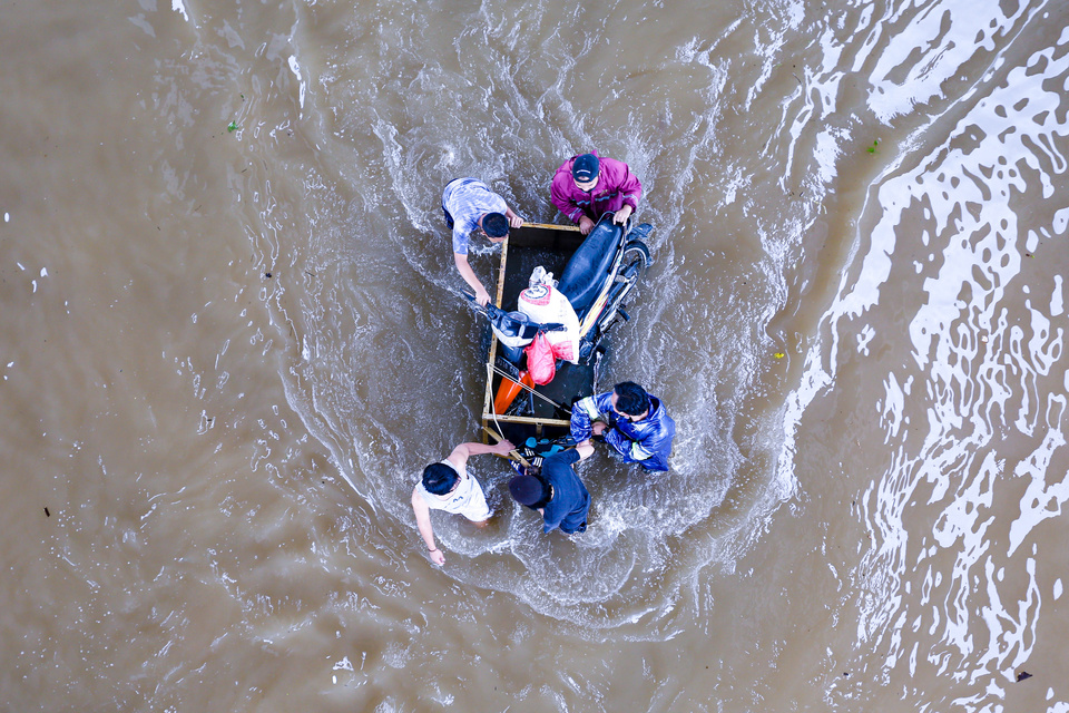 Residents transport a motorcycle using a wooden cart along Jalan Ciledug Raya submerged as deep as 1 meter in Pesanggrahan, South Jakarta, on Feb. 20, 2021. (Beritasatu Photo/Ruht Semiono)