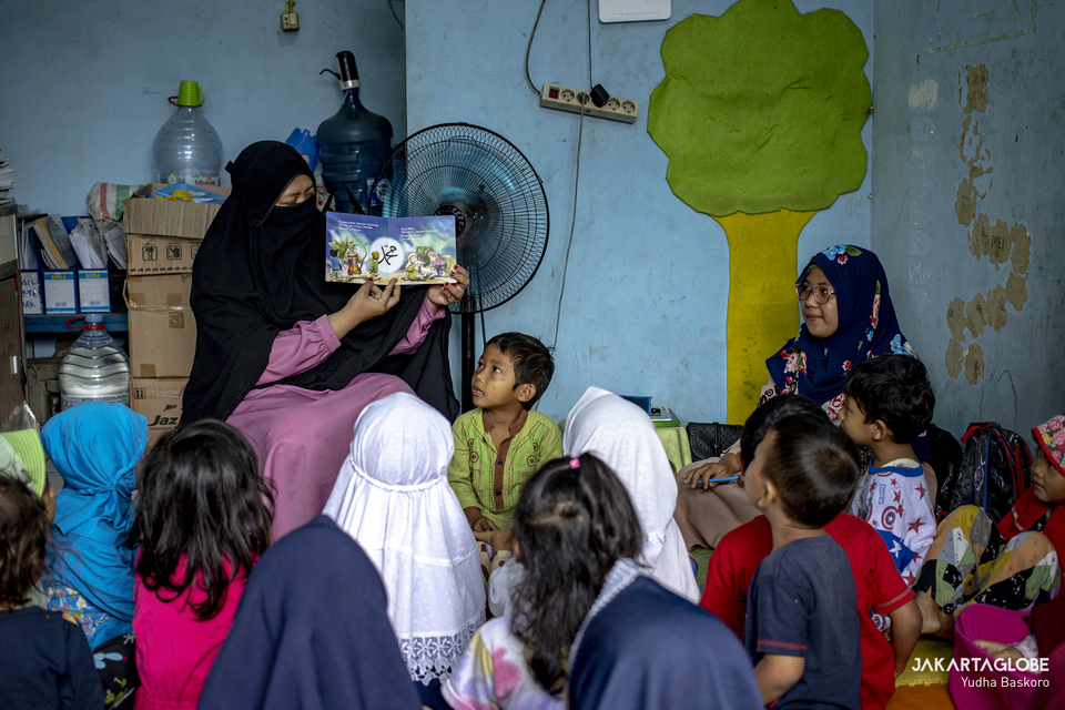 Desi Purwatuning, 42, reads a story book to her students at Rumah Belajar Merah Putih in Kojem, North Jakarta on Feb. 19, 2021. (JG Photo/Yudha Baskoro)