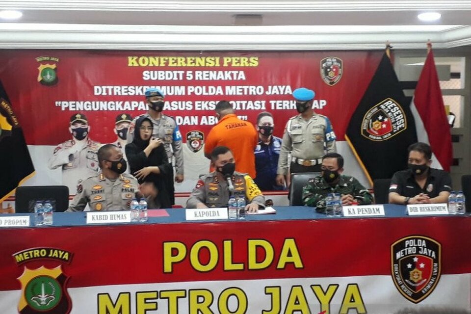 Jakarta Police Chief Insp. Gen. Fadil Imran, second from left, briefs reporters about the fatal shooting in a Jakarta bar with the suspect, an active police officer, standing at the background wearing orange detainee shirt in Jakarta on Feb. 25, 2021. (Antara Photo)