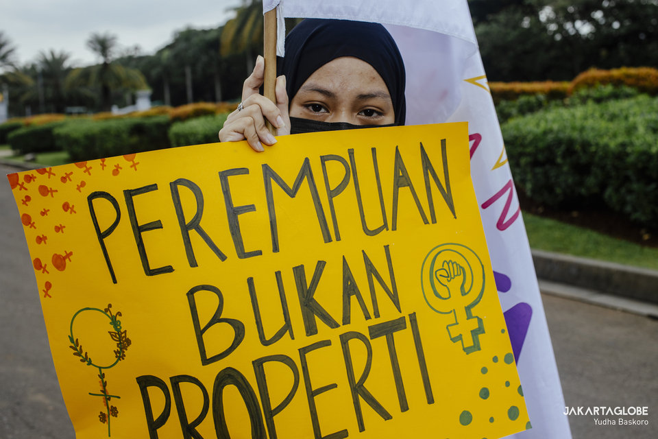 A woman carries a placard that reads “Women are not Property” during International Women's Day commemoration near Arjuna Wijaya statue in Central Jakarta on March 8, 2021. (JG Photo/Yudha Baskoro)
