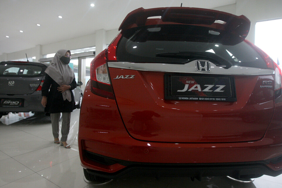 A saleswoman stands beside a now-discontinued Honda Jazz car in a dealer showroom in Bekasi, West Java, on March 4, 2021. (B1 Photo/Juanito de Saojoao)
