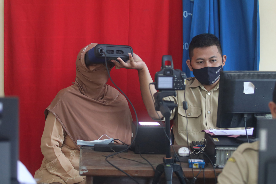 A government official records biometric data from a woman for making her electronic ID card in Kediri, East Java, on April 13, 2021. (Antara Photo/Prasetia Fauzani)