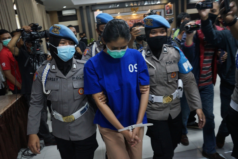 Nani Aprilliani, center, is escorted by two policewomen at the Bantul Police office in Yogyakarta on May 3, 2021. (Antara Photo/Andreas Fitri Atmoko)