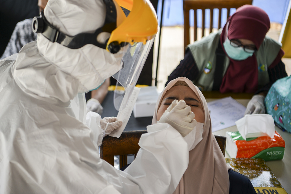 A medical worker collects a nasal swab sample from a traveler in Subang, West Java, on Friday. (Antara Photo/Hafidz Mubarak A)